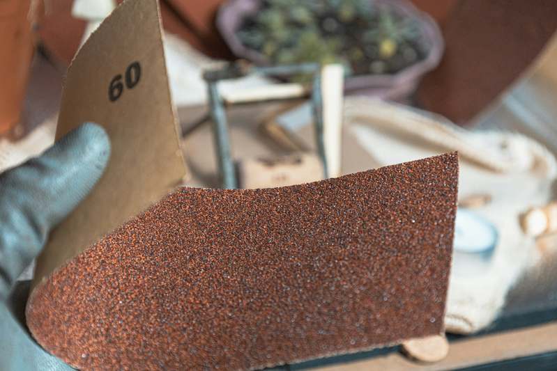 Close-up of worn abrasive discs on a metal workshop table with safety goggles and angle grinder nearby